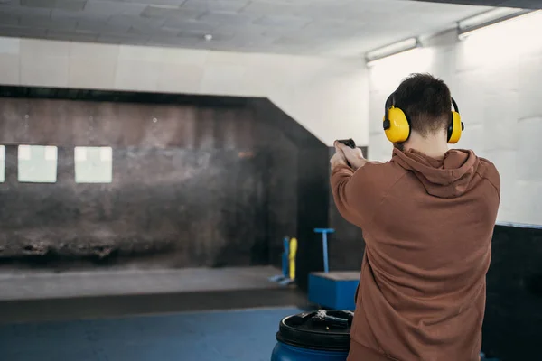 A man shoots a pistol at a target in a shooting range. Sports entertainment. Hitting the target