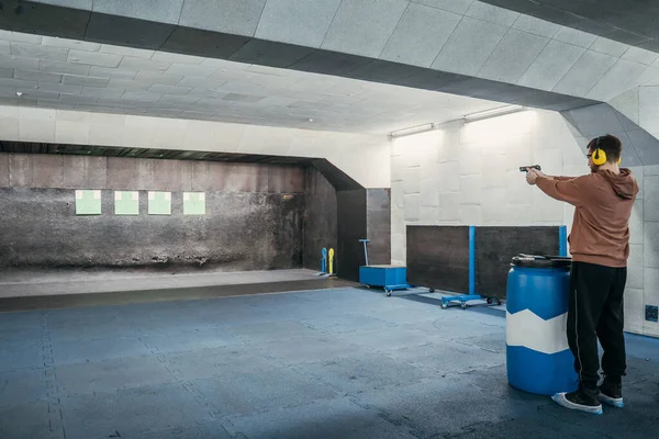 Long range shooting in a shooting range. A man shoots a short-barreled weapon at a target.