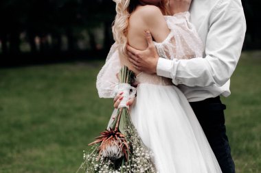 Doğada bir çiftin düğün sarılması ve bir buket çiçek.