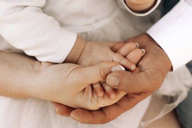 Anne ve baba çocuğun elini tutuyor.