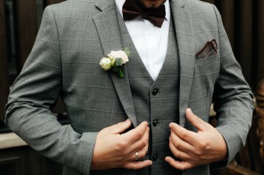 Takım elbiseli ve papyonlu bir adam ceketini, iş yerini ve düğün konseptini düzeltir.