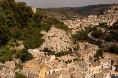 Sicilyalı Ragusa Ibla 'nın panoramik şehir manzarası. Kum taşından evler, kavisli yollar ve ağaçlar. Parlak güneşli manzara fotoğrafı turistik broşürler, seyahat şirketi web sitesi, posterler vs. için iyi.