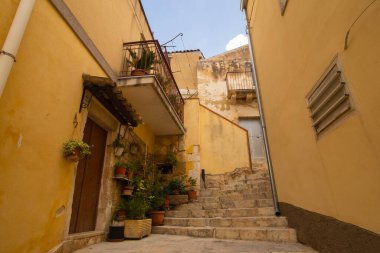 Eski Sicilya Modika şehrinin şehir manzarası. Kum taşından evler, merdivenler, balkonlar, avlularda kimse yok. Parlak güneşli fotoğraf turistik broşürler, seyahat şirketi web sitesi vs. için iyidir