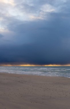 Baltık Denizi Curonian tükürük plajı dikey fotoğrafında kış ya da sonbahar sonu. Kum, koyu mavi deniz ve dramatik bulutlu gökyüzü. Gün batımı ışıklarıyla birlikte. Etrafta kimse yok, üzgün ve depresif..