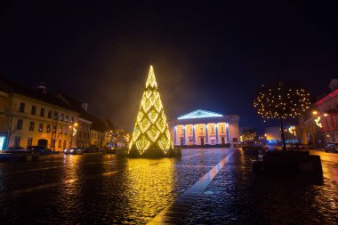 Vilnius, Litvanya - 01-01-22: Şehir merkezi belediye binası sokak aydınlatması ve yağmurlu, sisli bir yeni yıl gecesi bir Noel ağacı süslemesi. Sokakta kimse yok.