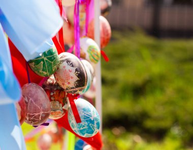 Renkli Paskalya yumurtalarının kompozisyonu. Renkli kurdelelerle birlikte. Metin için boş kopya alanı olan parlak güneşli bir fotoğraf.