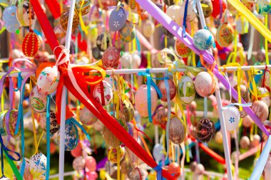 Renkli Paskalya yumurtalarının kompozisyonu. Renkli kurdelelerle birlikte. Parlak güneşli bir fotoğraf.