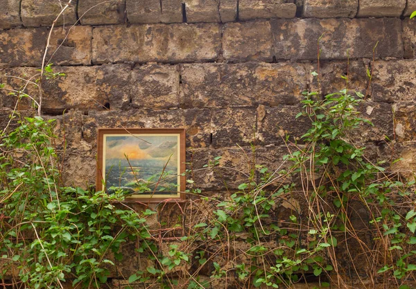 Odessa, Ukraine - 04 24 21: a wall with framed painting in a typical Odessa old town courtyard. Dirty scratched brick walls, green wine and decoration. Bright warm photo with copy space for text — Stock Photo, Image