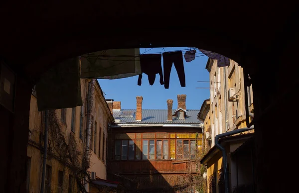Odessa, Ukraine - 04 22 21: An arch to enter classic Odessa old yard. Bright sunny spring atmospheric photo with vintage courtyard, dirty scratched walls and linen and clothes drying on clothesline — Fotografia de Stock