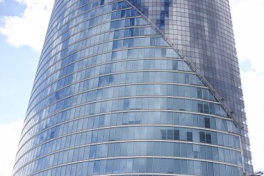 Soyut modern gökdelen mimarisini kapatın. Arka planda bulutlar olan uzun cam bina. Fotoğraf, sıcak bulutlu bir yaz gününde çekildi..