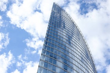 Soyut modern gökdelen mimarisini kapatın. Arka planda bulutlar olan uzun cam bina. Fotoğraf, sıcak bulutlu bir yaz gününde çekildi..