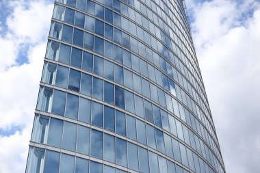 Soyut modern gökdelen mimarisini kapatın. Arka planda bulutlar olan uzun cam bina. Fotoğraf, sıcak bulutlu bir yaz gününde çekildi..