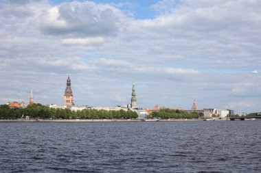 Eski Riga mimari binalarının ve Daugava nehri yakınlarındaki kiliselerin şehir manzarası. Fotoğraf, sıcak bir yaz bulutlu bir günde çekildi..