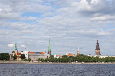 Eski Riga mimari binalarının ve Daugava nehri yakınlarındaki kiliselerin şehir manzarası. Fotoğraf, sıcak bir yaz bulutlu bir günde çekildi..