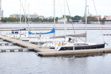 Suyun yanında küçük bir yat iskelesi ve birkaç yay. Fotoğraf sıcak ve bulutlu bir yaz gününde çekildi..