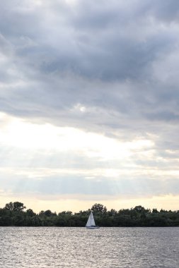 Deniz manzaralı bulutlu gökyüzü ve sakin nehirde yüzen yalnız bir tekne. Fotoğraf sıcak bir yaz gününde çekildi..