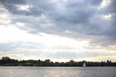 Deniz manzaralı bulutlu gökyüzü ve sakin nehirde yüzen yalnız bir tekne. Fotoğraf sıcak bir yaz gününde çekildi..