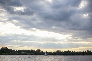 Deniz manzaralı bulutlu gökyüzü ve sakin nehirde yüzen yalnız bir tekne. Fotoğraf sıcak bir yaz gününde çekildi..