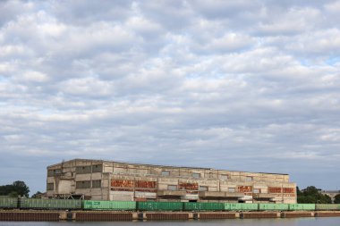 Kargo treni rıhtımdaki eski tuğla binanın yanında duruyor. Fotoğraf bulutlu bulutlu sıcak bir günde çekildi..