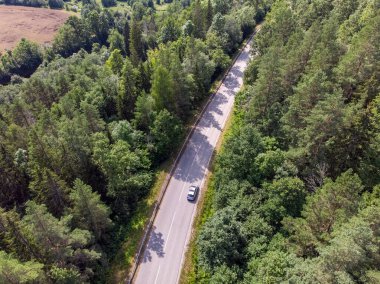 Tek arabalı otobanın gerçek bir insansız hava aracı görüntüsü. Yolun iki tarafında da orman var..