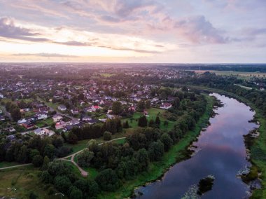 Akşamın geç saatlerinde insansız hava aracı küçük özel evlerle günbatımını izliyor. Fotoğraf, bulutlu ve sıcak bir havada çekildi..