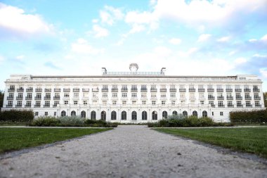 Önünde bahçe olan büyük beyaz binanın arka dış görünüşü. Fotoğraf sıcak, güneşli bir sonbahar gününde çekildi..
