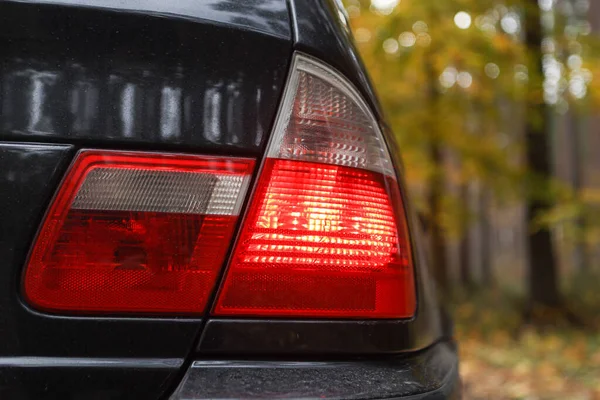 Arka taraf BMW E46 kırmızı araba ışıklarını kapatın. Fotoğraf, arka planda sonbahar renkleri olan bulutlu bir sonbahar gününde çekildi.