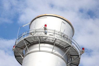 Metalik baca kulesinin yakın çekim sanayi görüntüsü. Fotoğraf bulutlu bir günde gökyüzünde birçok bulutla çekildi.