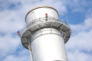 Metalik baca kulesinin yakın çekim sanayi görüntüsü. Fotoğraf bulutlu bir günde gökyüzünde birçok bulutla çekildi.