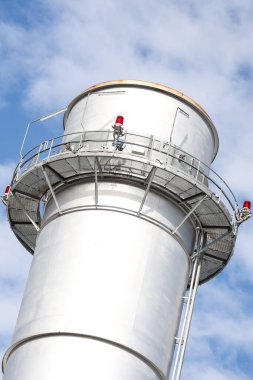 Metalik baca kulesinin yakın çekim sanayi görüntüsü. Fotoğraf bulutlu bir günde gökyüzünde birçok bulutla çekildi.