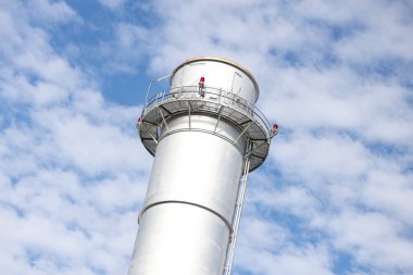 Metalik baca kulesinin yakın çekim sanayi görüntüsü. Fotoğraf bulutlu bir günde gökyüzünde birçok bulutla çekildi.