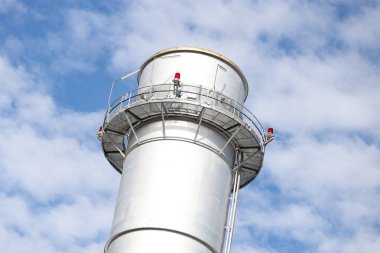 Metalik baca kulesinin yakın çekim sanayi görüntüsü. Fotoğraf bulutlu bir günde gökyüzünde birçok bulutla çekildi.