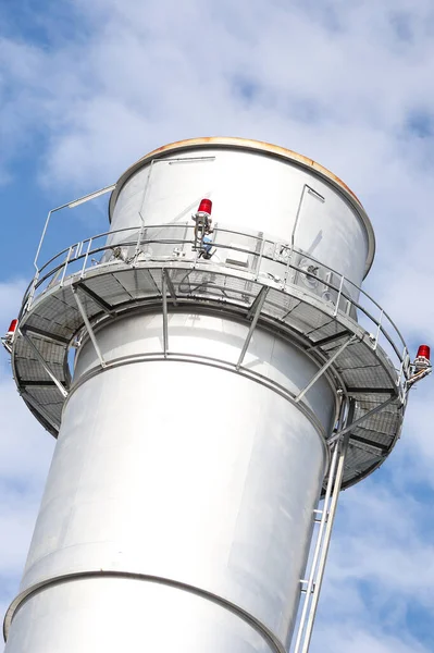 Metalik baca kulesinin yakın çekim sanayi görüntüsü. Fotoğraf bulutlu bir günde gökyüzünde birçok bulutla çekildi.