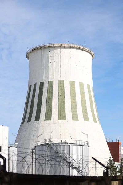 Büyük beyaz termik santral bacasının yakın çekimleri. Fotoğraf mavi bulutlu gökyüzünün önünde çekildi.