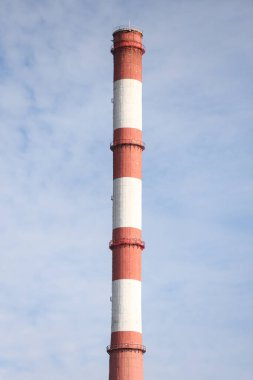 Tall, thin Two Color red and white chimney on the background of blue sky with clouds. Photo taken on a warm overcast autumn day.