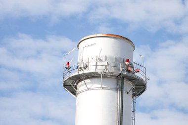 Small silver color electric plant chimney. Photo taken on a sunny autumn day with many small clouds in the background.