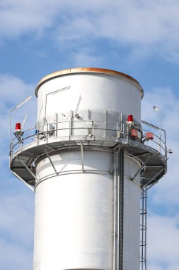 Small silver color electric plant chimney. Photo taken on a sunny autumn day with many small clouds in the background.