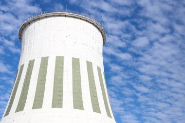 Large white chimney for power plant station with no smoke. Photo taken on a warm overcast autumn day on the foreground of beautiful blue sky with many white clouds