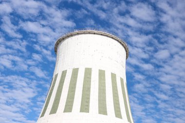 Large white chimney for power plant station with no smoke. Photo taken on a warm overcast autumn day on the foreground of beautiful blue sky with many white clouds