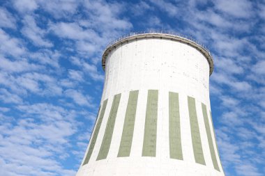 Large white chimney for power plant station with no smoke. Photo taken on a warm overcast autumn day on the foreground of beautiful blue sky with many white clouds