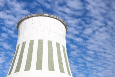 Large white chimney for power plant station with no smoke. Photo taken on a warm overcast autumn day on the foreground of beautiful blue sky with many white clouds