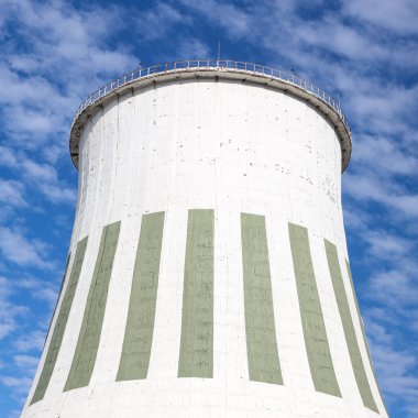 Large white chimney for power plant station with no smoke. Photo taken on a warm overcast autumn day on the foreground of beautiful blue sky with many white clouds