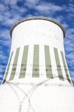 Large power plant white chimney with  unsharp barbed wires in foreground. Photo taken on a warm overcast autumn day.