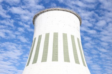 Large power plant white chimney with  unsharp barbed wires in foreground. Photo taken on a warm overcast autumn day.