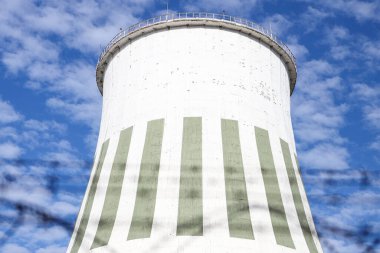 Large power plant white chimney with  unsharp barbed wires in foreground. Photo taken on a warm overcast autumn day.