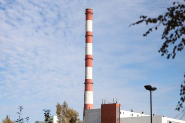 Tall, thin Two Color red and white chimney on the background of blue sky with clouds. Photo taken on a warm overcast autumn day.