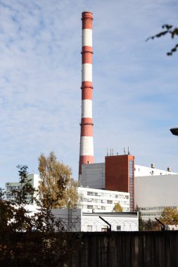 Tall, thin Two Color red and white chimney on the background of blue sky with clouds. Photo taken on a warm overcast autumn day.