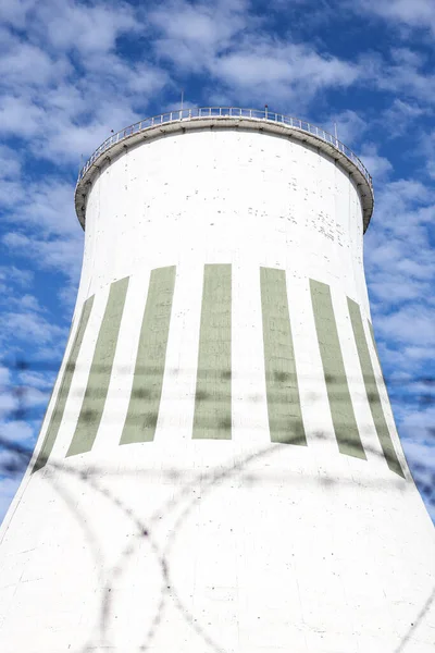 Large power plant white chimney with  unsharp barbed wires in foreground. Photo taken on a warm overcast autumn day.