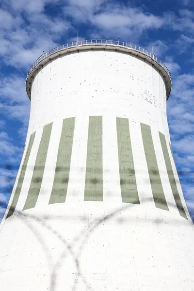 Large power plant white chimney with  unsharp barbed wires in foreground. Photo taken on a warm overcast autumn day.