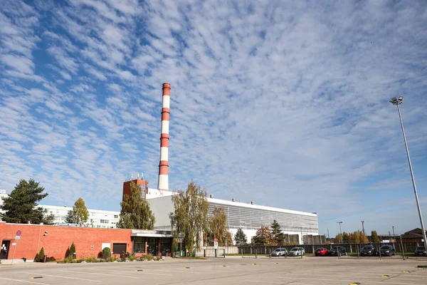 Large, tall electricity thermal power plant red, white color chimney building factory. Photo taken on a warm overcast autumnd ay with blue sky and white clouds.